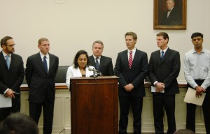 Bindu Phillips of Plainsboro, N.J. addresses media at a Capitol Hill press conference. From left in rear are other “left-behind” parents Barton Hermer of Texas, Paul Toland of Maryland, Rep. Chris Smith, David Goldman of N.J., Dennis Burns of Colorado, and Arvind Chawdra of N.J.